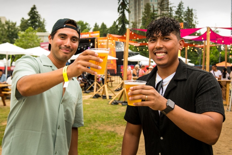Two people smiling holding a beer.