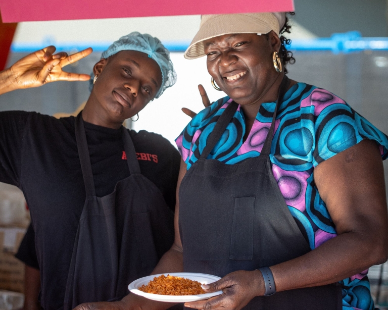 Two people smiling and holding food.