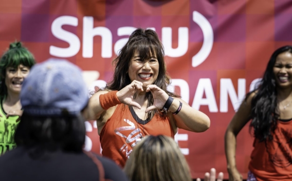 Zumba dancer makes a heart sign with her hands to the audience watching